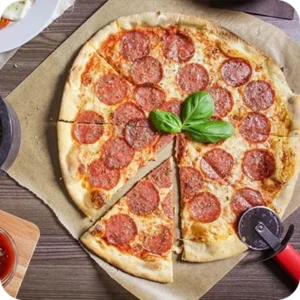 A sliced pepperoni pizza topped with fresh basil