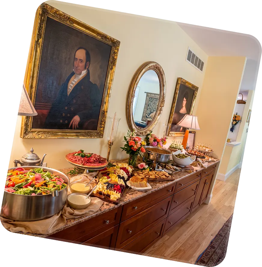 Buffet laid along a sideboard under framed portraits at an indoor event