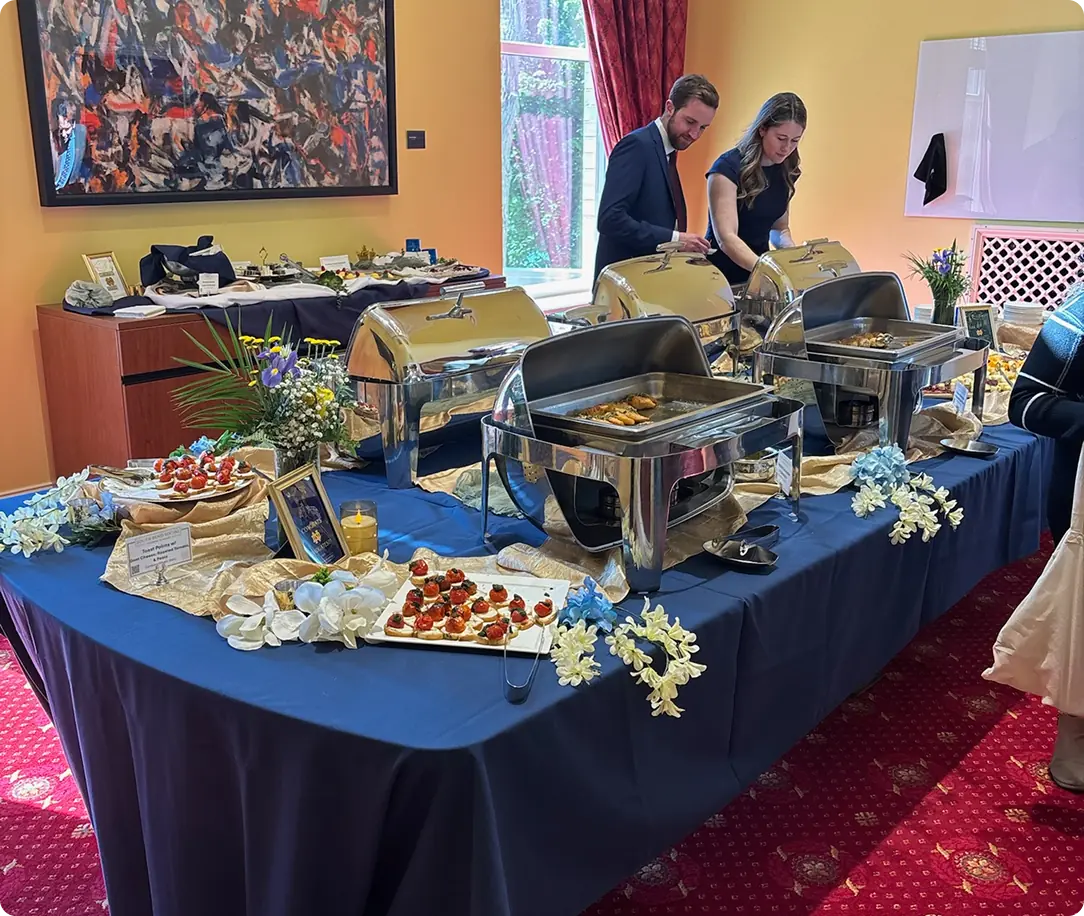 Chafing dishes and platters set out on a blue linen buffet table